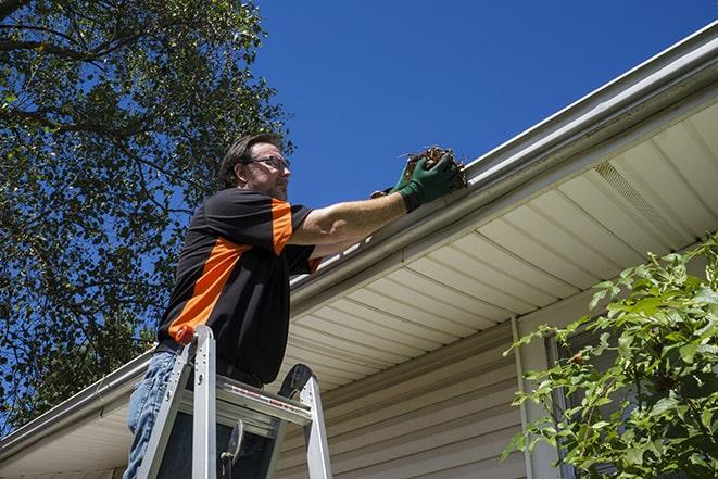 a repairman inspecting a clogged gutter for debris in Half Moon Bay, CA